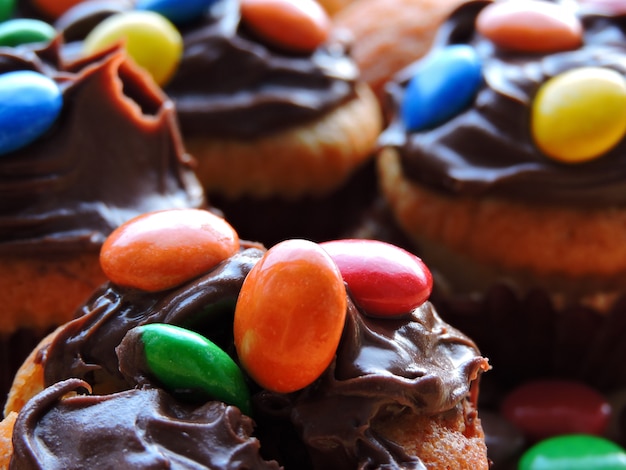 Mini muffins with topping from chocolate cream and colored sweets.