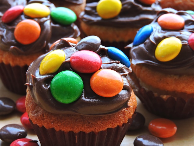 Mini muffins with topping from chocolate cream and colored sweets.