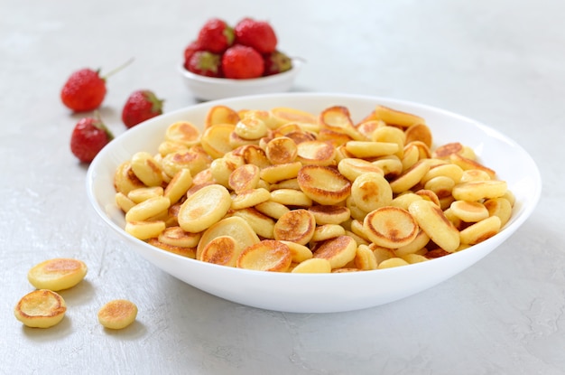 Mini pancakes in a bowl on a light background