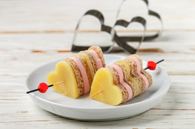 Mini sandwiches parmesan cheese ham bread on skewers in the form of hearts,