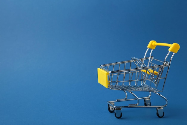 Mini shopping trolley on blue background Top view