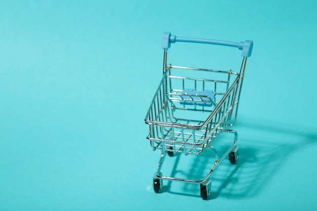 Mini shopping trolley with shadow on blue background Top view