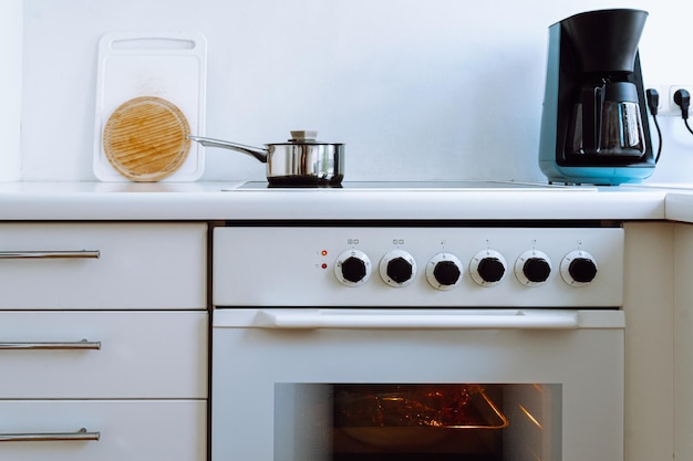 Mini small white cozy and cfurniture with white facades, electric hob and oven for small apartment.