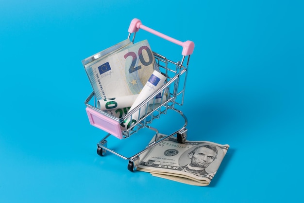 Mini supermarket shopping cart with various international currencies dollar euro real