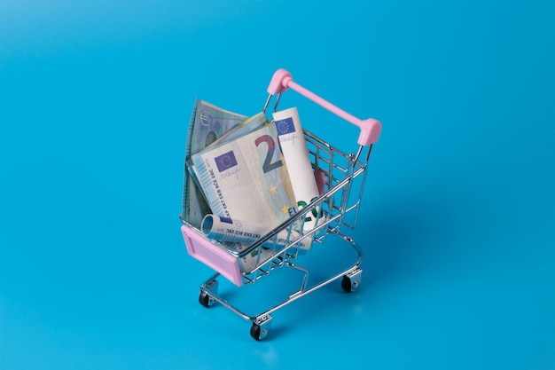 Mini supermarket shopping cart with various international currencies dollar euro real