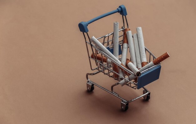 Mini supermarket trolley with cigarettes on brown background