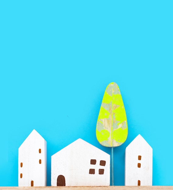 Mini wooden house model with tree on blue background