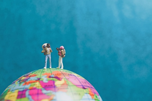 Photo miniature backpacker travelers with backpack standing on world map and walking to destination