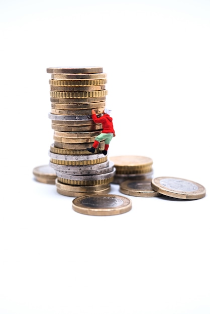 Miniature climber climbing on the stack of coins