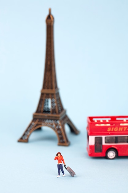 miniature Eiffel tower and women tourist on blue background