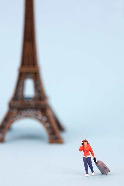 miniature Eiffel tower and women tourist on blue background