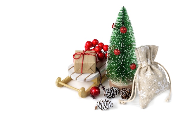 Miniature fir tree with Christmas gifts on the sleigh isolated on white background.