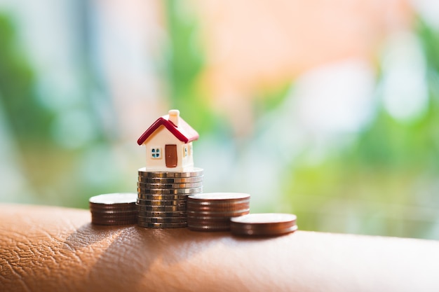 Miniature house standing on stack coins