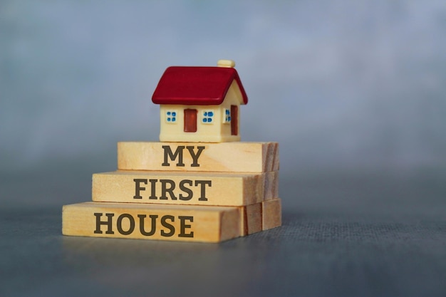 Photo miniature house on top of wooden tiles with text my first house