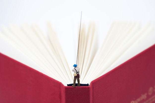 Miniature man fishing on a book