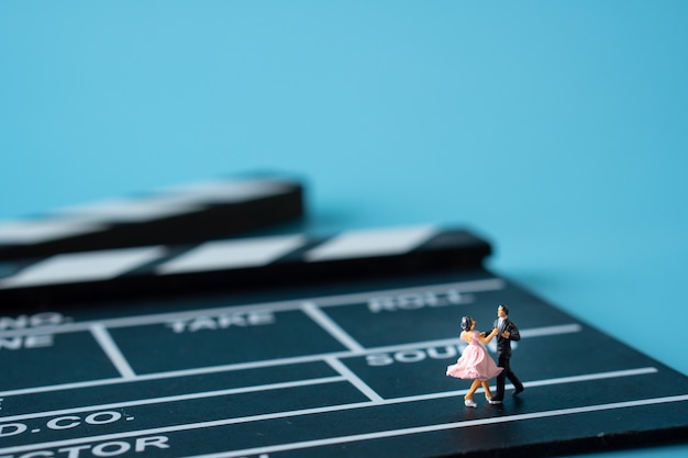 Miniature of Man in suit and woman in pink dress dancing on clapperboard.