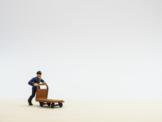 Miniature man with trolley on white background.