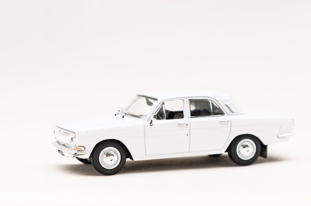 Miniature model of a toy white retro car on a white surface