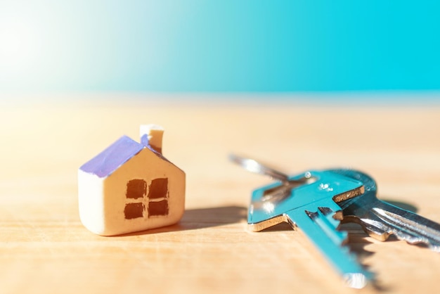 Miniature new house with house keys on wooden blue blurred background