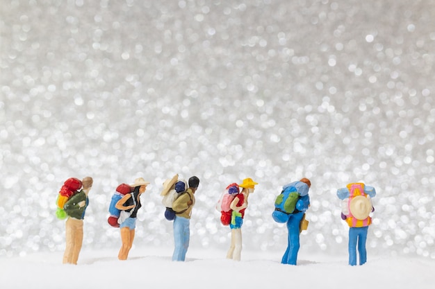 Miniature people, backpacker walking on snow