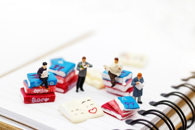 Miniature people: Business team reading book, education concept.