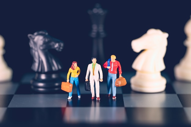 Miniature people, business team standing on chess board background using as business strategy concept