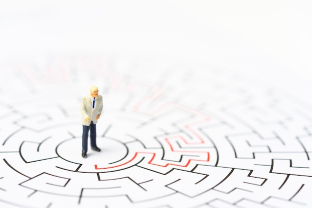 Miniature people, businessman in the labyrinth or maze figuring out the way out. 