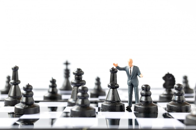 Miniature people Businessman standing on chessboard