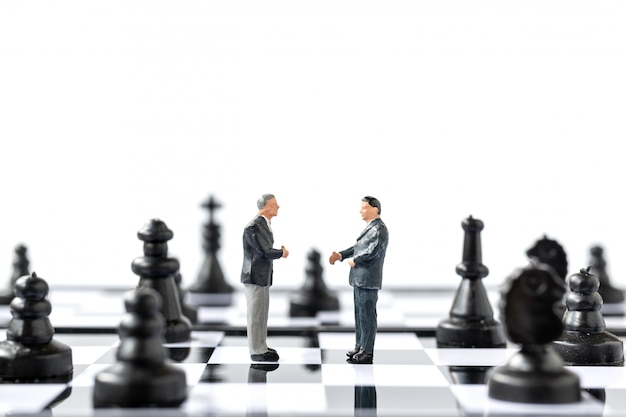 Miniature people Businessman standing on chessboard