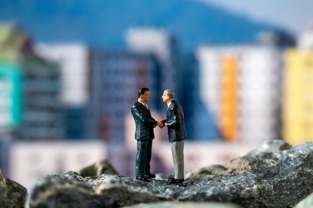 Miniature people , Businessman standing on The rock with building