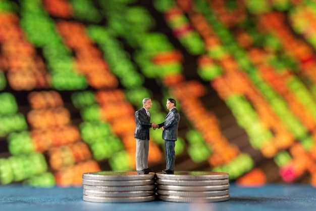 Miniature people , Businessman standing on stack of  Coins with graph display