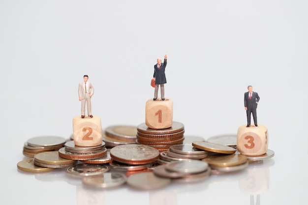 Miniature people: businessman standing on stacking coins 