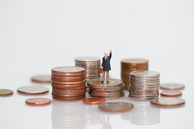 Miniature people: businessman standing on stacking coins 