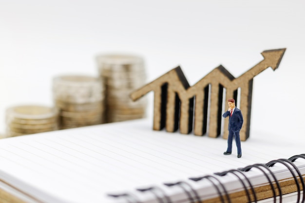 Miniature people:  Businessmen standing on coins stack with graph, Finance, investment and growth in business concept.