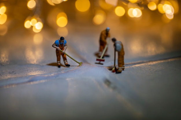 Miniature people cleaning tile floor with blur background.