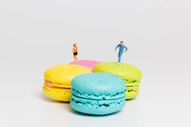 Miniature people , couple running on colourful french macaroon , 