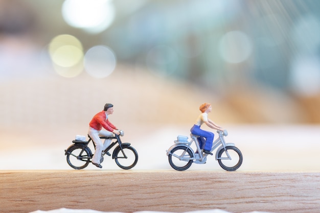 Miniature people  cycling on wooden bridge