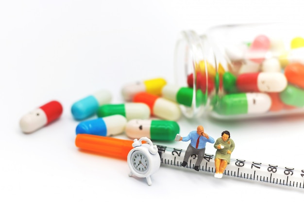 Miniature people, Fat Patients sitting on syringe with drugs and clock