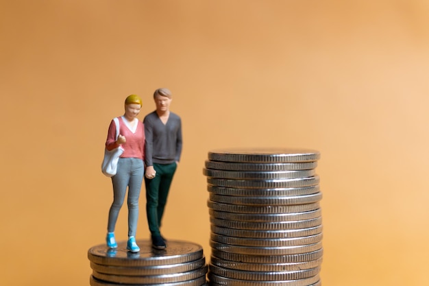 Miniature people Happy couple standing on coins stack