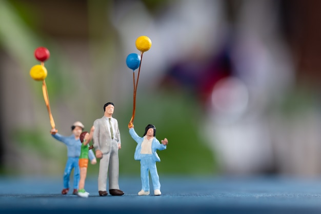 Miniature people: Happy family holding balloon in The park