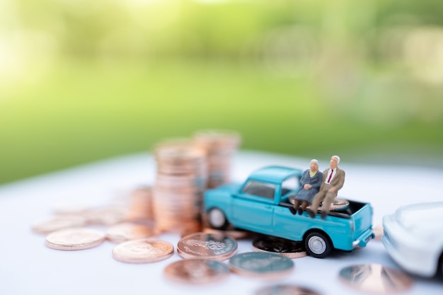 Miniature people: Happy old people sitting on coins stack, Retirement  and Life insurance Concept.