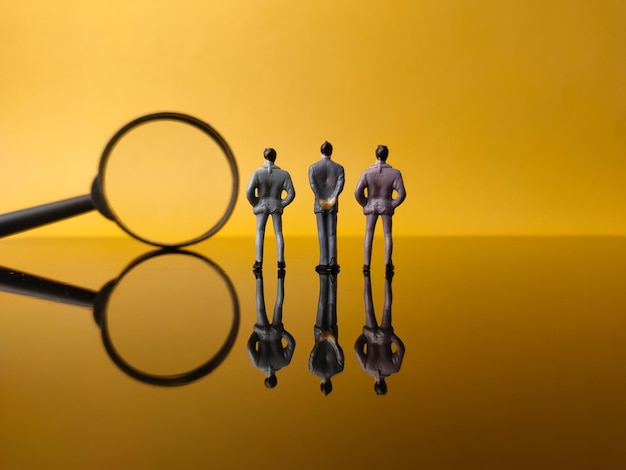 Miniature people and magnifying glass with reflection