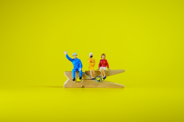 Miniature people, man and woman sitting on wooden clip using as business and social concept