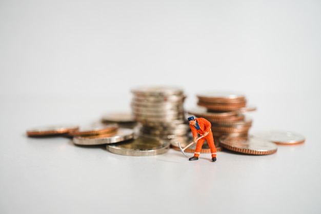 Miniature people, man working on stack coins background using as business and financial concept