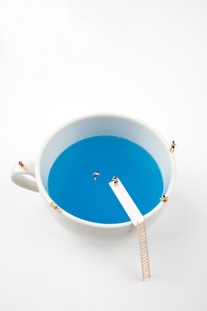 miniature people in mug cup swimming pool