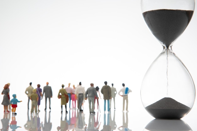 Miniature people people of different ages and statuses stand in line near the hourglass the concept of the importance of time and life