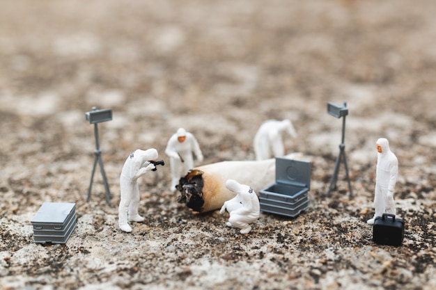 Photo miniature people: police and detective finding proof from old cigarette in crime scene