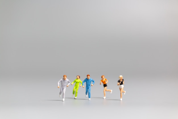 Miniature people Running on gray background and free space for text