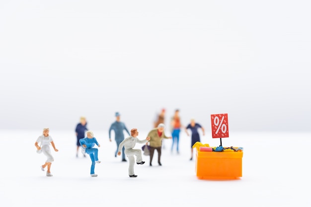 Miniature people, shoppers running to discount tray for shopping discounted items.