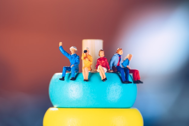 Miniature people sitting on colorful wooden block using as business and social concept